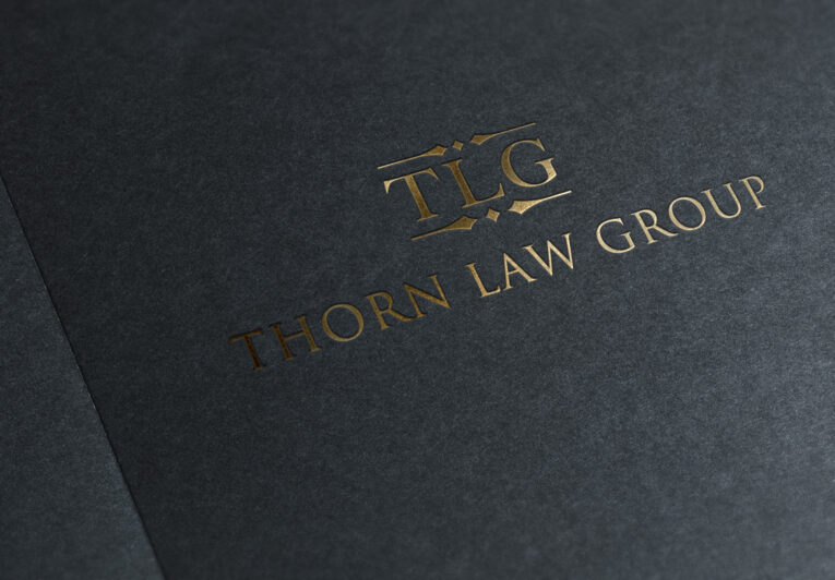 Close-up of a dark-colored legal folder with gold embossed text that reads "TLG Thorn Law Group," showcasing the elegance and professionalism, embodying the five characteristics of a great logo.