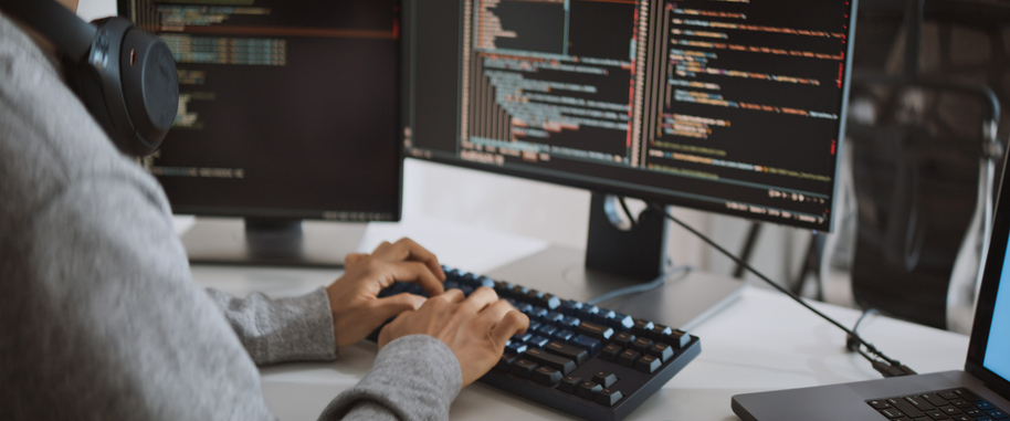Young adult male software developer coding program on desktop computer. Man work from home, remote working, freelance programmer job, smart digital nomad lifestyle concept. Close Up